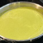 A stainless steel pan of roasted poblano sauce. The sauce is a vibrant, bright green in color.