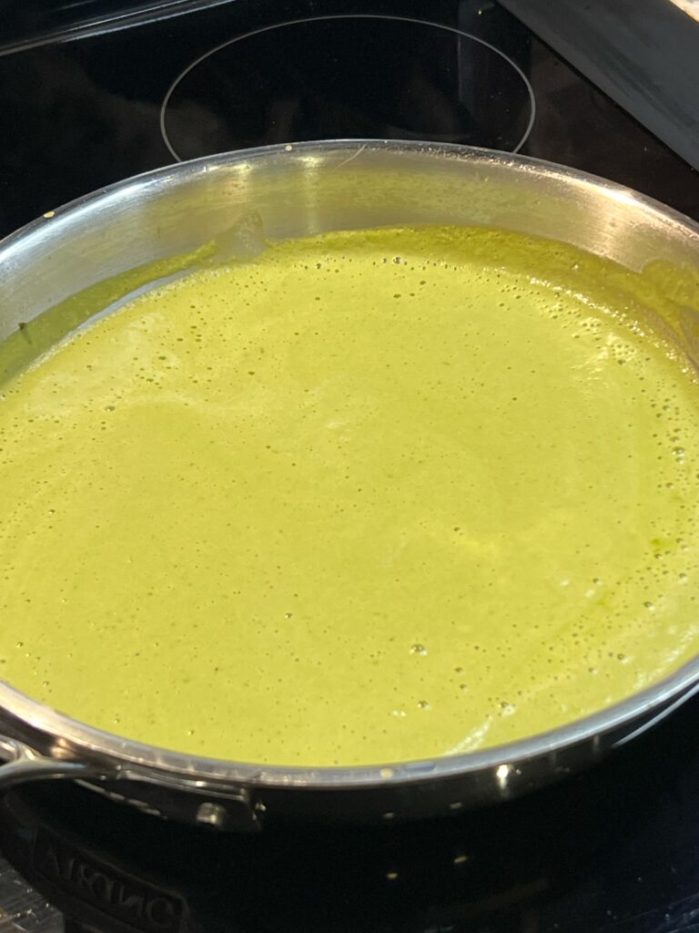 A stainless steel pan of roasted poblano sauce. The sauce is a vibrant, bright green in color.