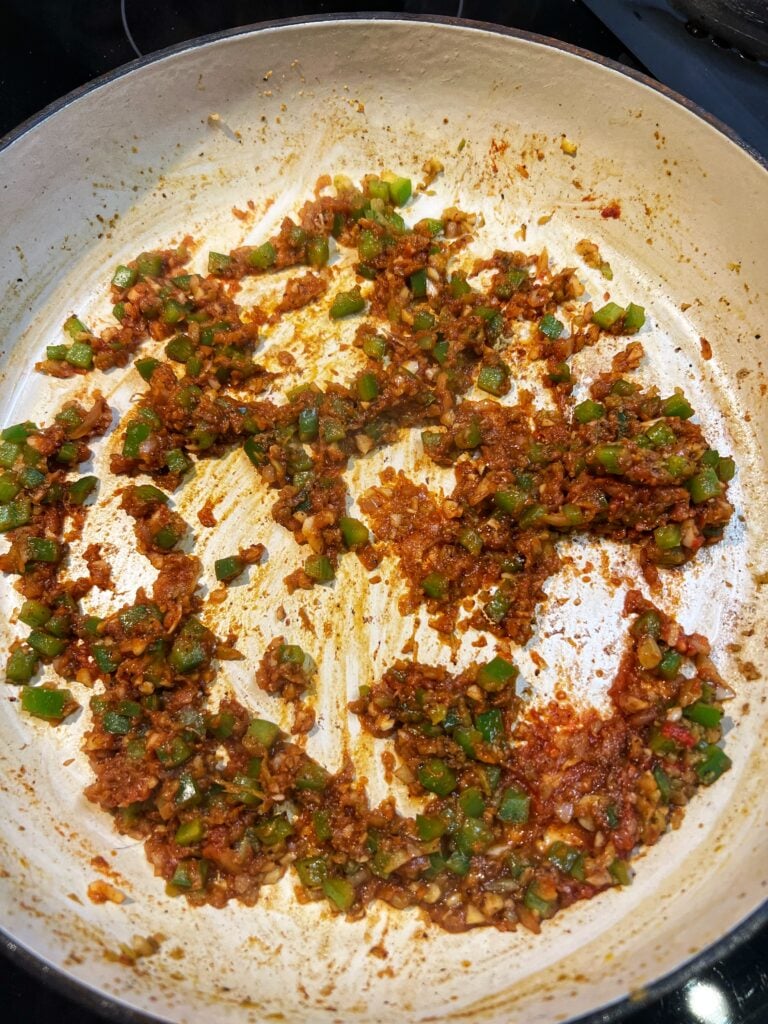 A pan of softened, diced bell peppers, onion, celery and tomato paste for Jambalaya.
