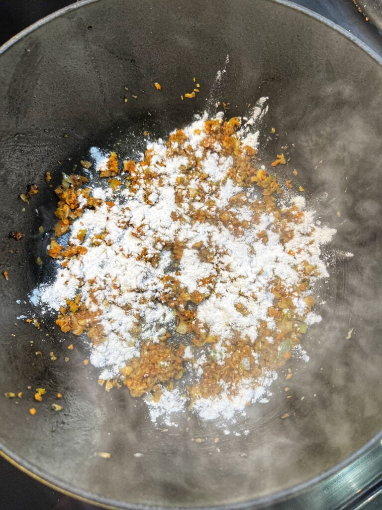 Minced, sautéed vegetables sprinkled with flour in a pot.