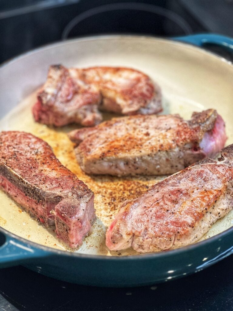 Seasoned country style pork ribs searing in a pan.
