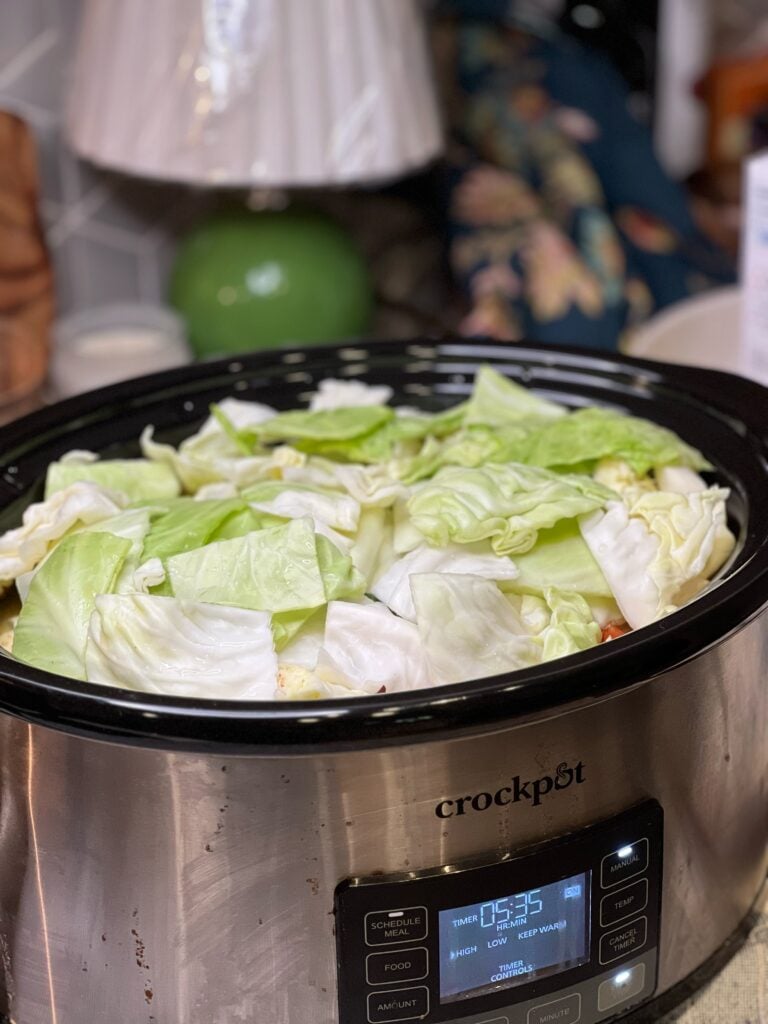 A slow cooker filled with large diced cabbage.