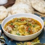 A white bowl of pork and cabbage stew that is garnish with fresh parsley.