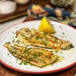 A plate of two seared flounder filets with lemon butter sauce.
