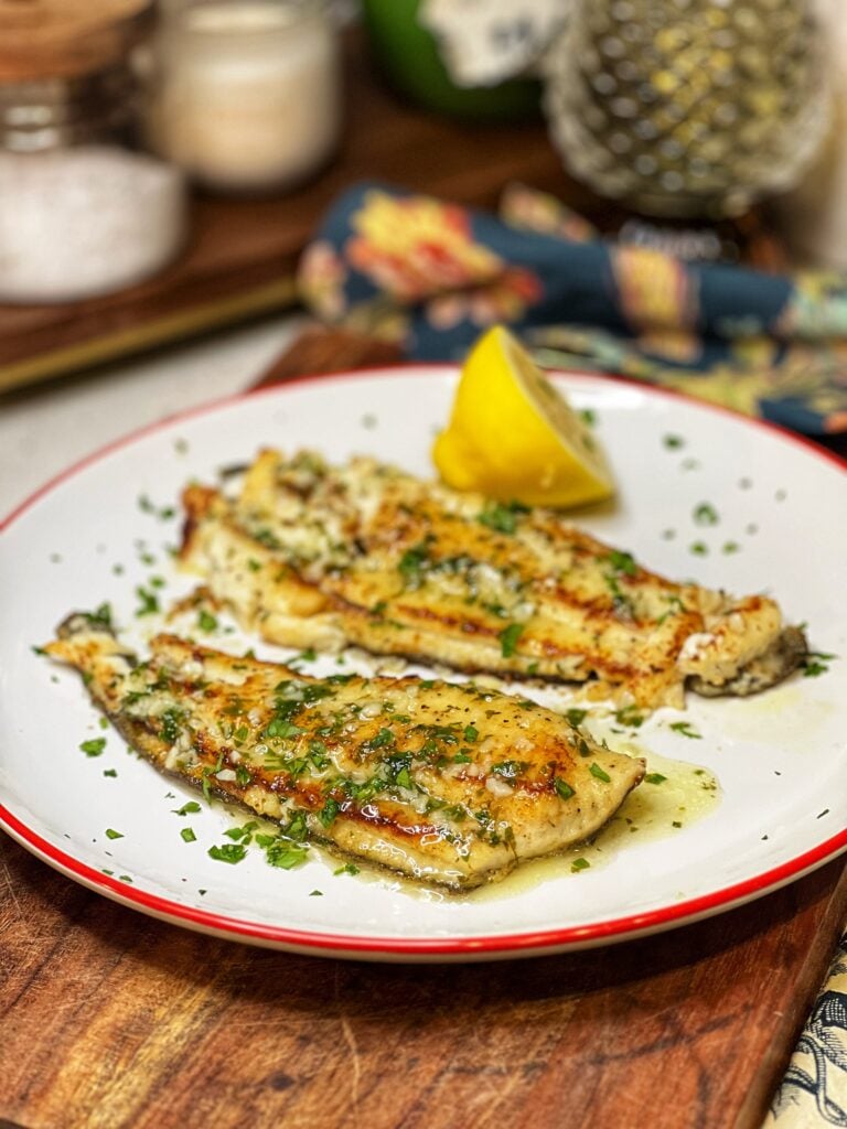 A plate of two seared flounder filets with lemon butter sauce.