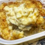 A spoonful of baked cauliflower au gratin taken out of a yellow casserole dish