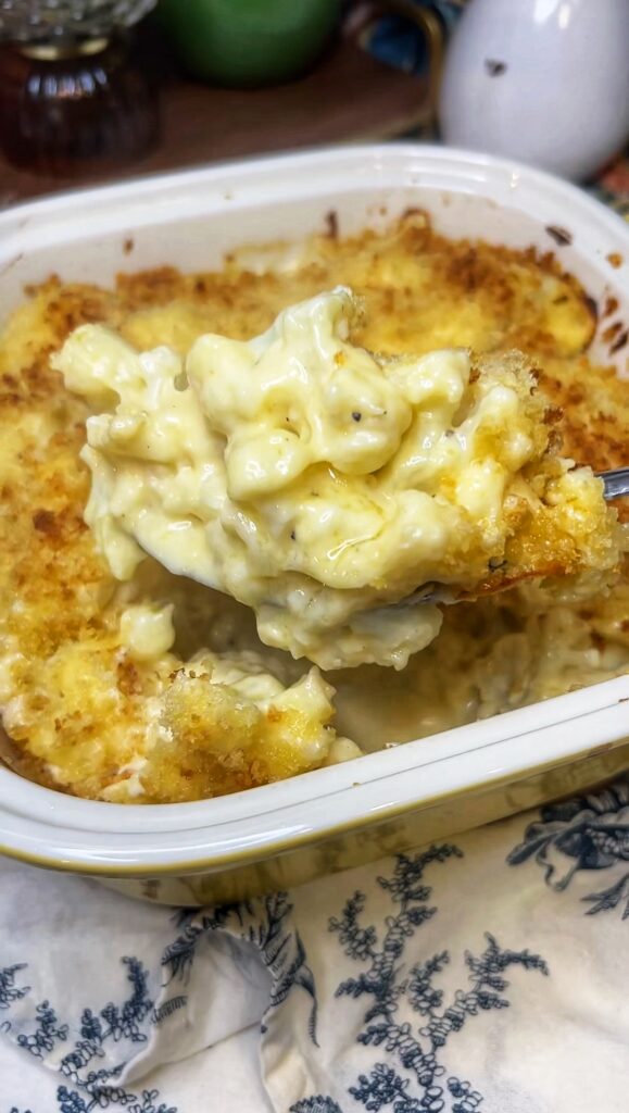 A spoonful of baked cauliflower au gratin taken out of a yellow casserole dish