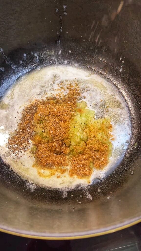 Minced onion, celery and garlic with seasonings sautéing in butter in a pot.
