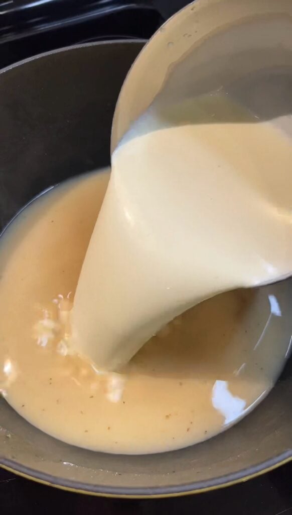 Pouring heavy cream into a pot.