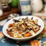 A white platter or roasted carrots with maple aioli. The sauce is white and the carrots are colorful.
