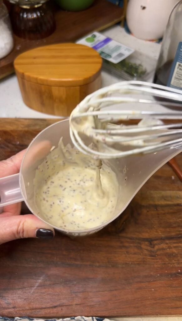 Whisking a maple mustard sauce in a plastic pourable measuring cup.