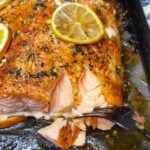 Showing the corner of a citrus herb butter salmon filet and how easily it's flaking with a fork after baking.