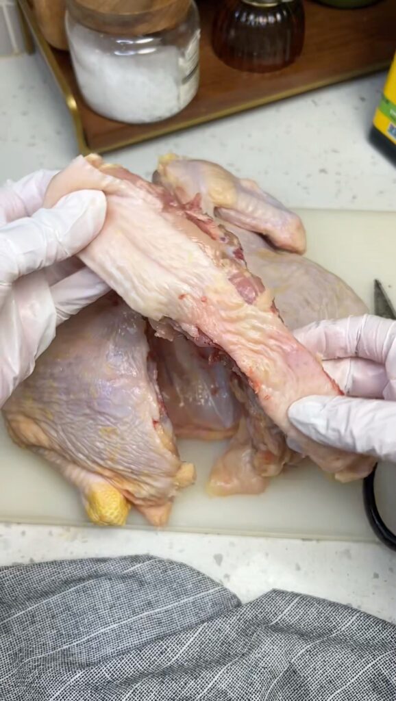 Holding the backbone of a whole chicken after I spatchcocked it.