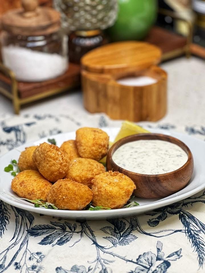 A platter of deep fried scallops that are served with tartar sauce and lemon wedge.