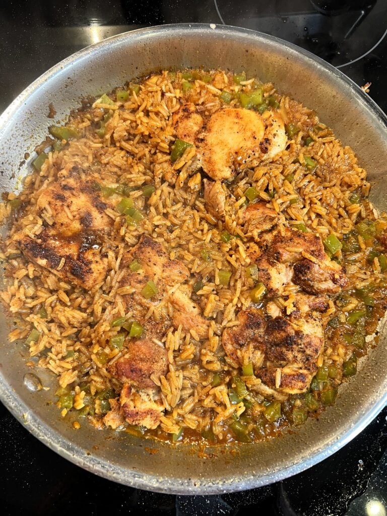 A stainless steel pan of Creamy Cajun Chicken and Rice. Boneless chicken thighs are seared and golden brown.