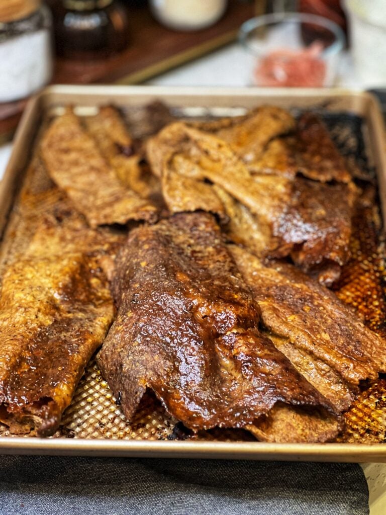 Doner kebab meat laying in a sheet pan. The meat is thin and browned.