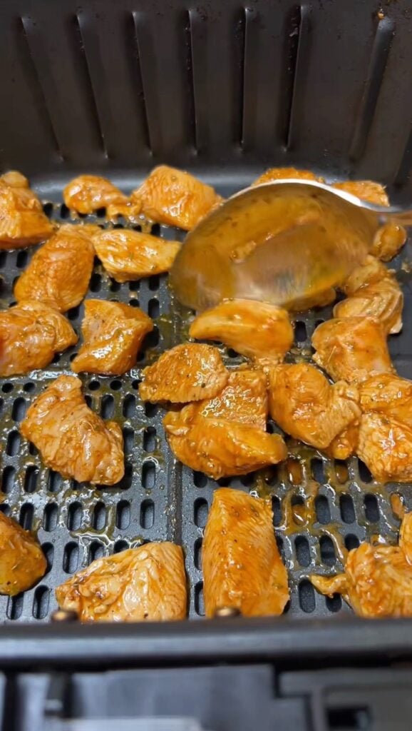 Marinated, diced chicken in an air fryer basket.