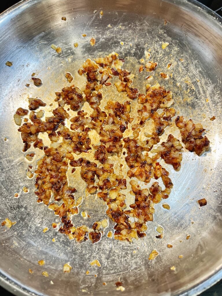 Diced Vidalia onions caramelized in a stainless steel pan.