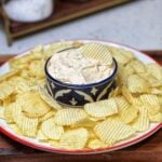 A round platter of Ruffles chips surrounding a bowl of Creamy Vidalia Onion Dip.