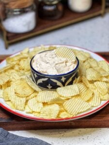 A round platter of Ruffles chips surrounding a bowl of Creamy Vidalia Onion Dip.