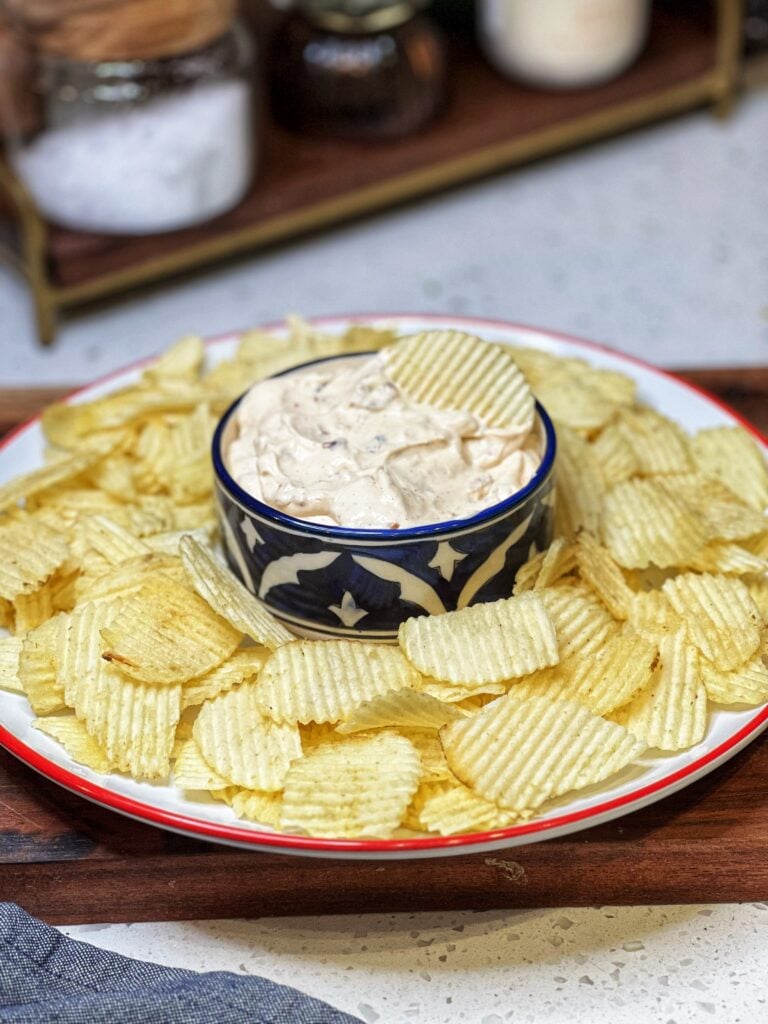 A round platter of Ruffles chips surrounding a bowl of Creamy Vidalia Onion Dip.