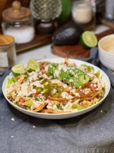 A white bowl of street corn taco salad. The base is Romaine lettuce with tomatoes, corn, tortilla strips, avocado and a creamy dressing.