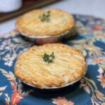 Two chicken cordon bleu pot pies garnished with a fresh thyme sprig.