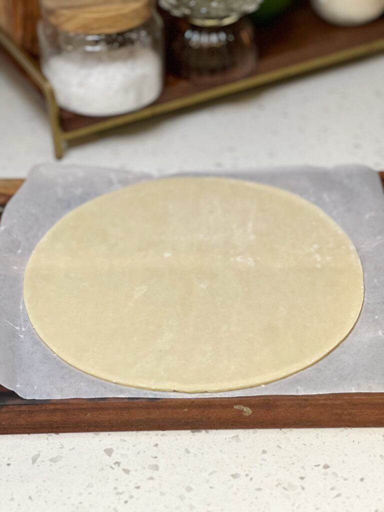 A round, frozen Wick's pie crust on a piece of white parchment paper.