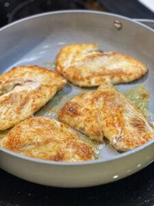 Four pieces of trigger fish sautéing in a non-stick pan.