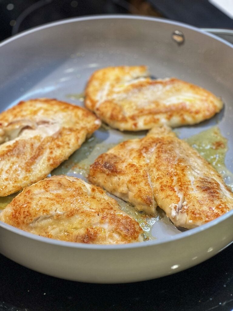 Four pieces of trigger fish sautéing in a non-stick pan.