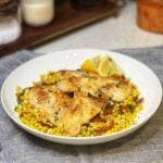 Two pan sautéed trigger fish resting on a bed of brown butter corn in a bowl.