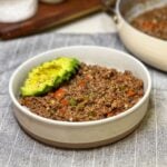 A white bowl filled with steamed rice and topped with Black Pepper Ground Beef, and sliced avocado.