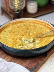 Cheesy Broccoli Rice Casserole shown with a spoonful of the rice coming out of the bluish green pan.