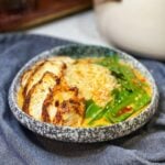 A curry chicken rice bowl. Steamed rice is in a bowl with snow peas, chicken and a creamy broth.