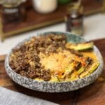 A Curry Beef Broth Bowl. A mound of steamed rice is served with crispy ground beef and seared zucchini spears on the side with a coconut curry broth on top and a drizzle of chili oil.